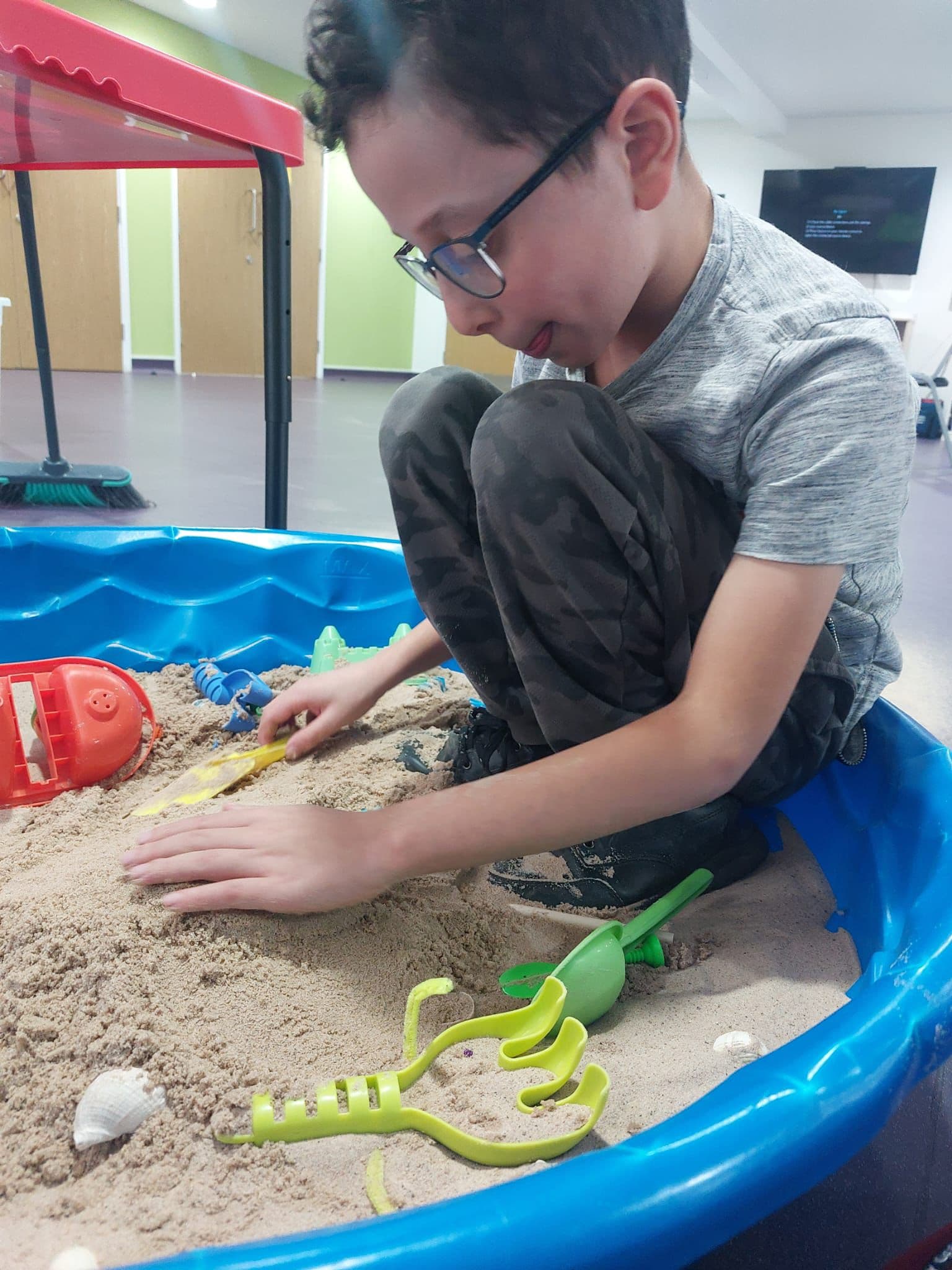 Child exploring sand play with tools and toys for sensory development