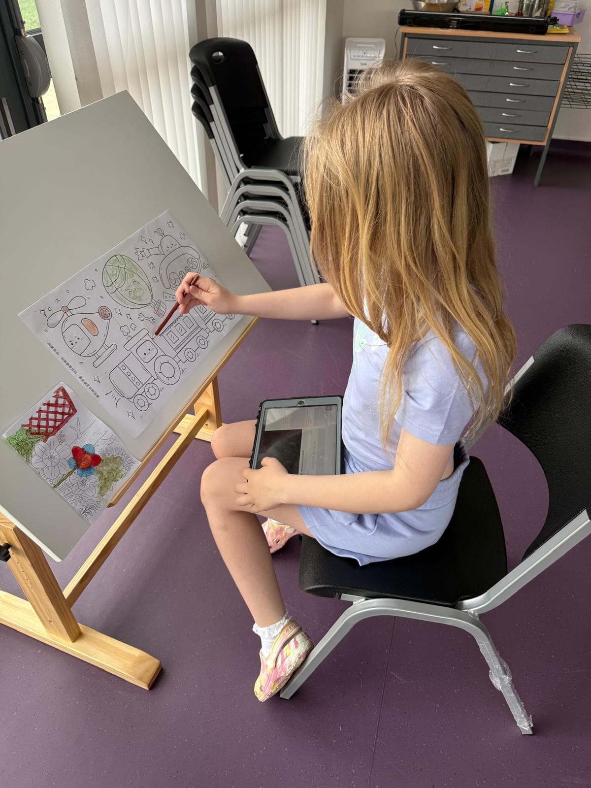 Child focused on colouring at an easel during a creative session