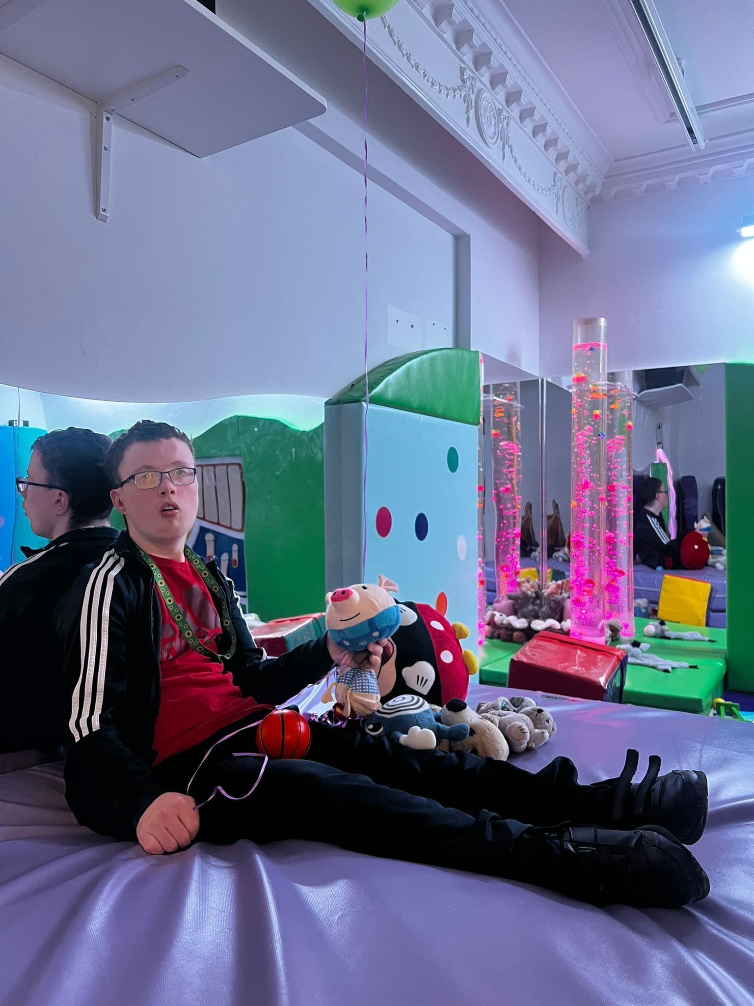 Child relaxing in the sensory room with bubble tubes and soft toys