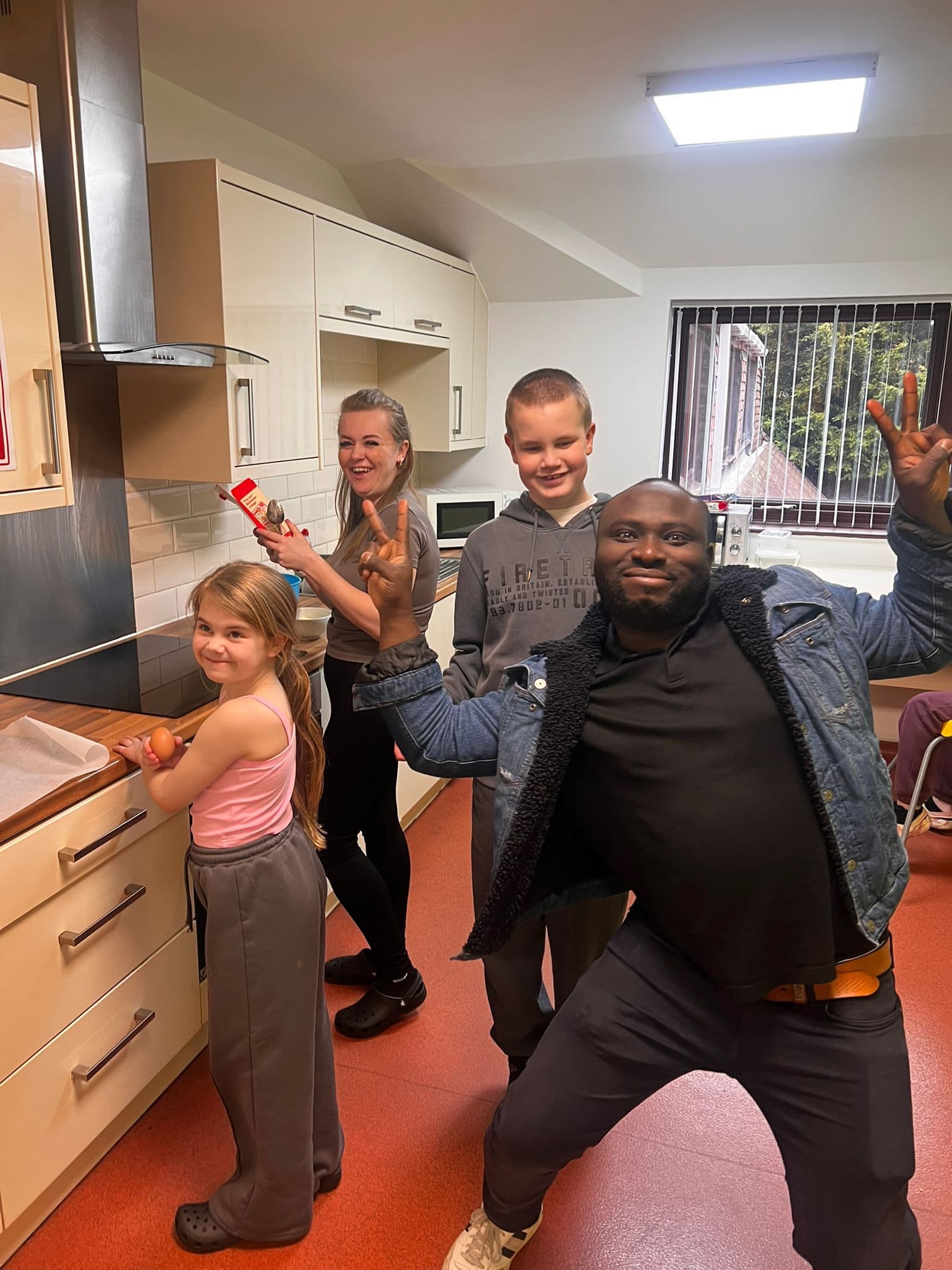 Staff and children together in the kitchen, smiling during a cooking and life skills session